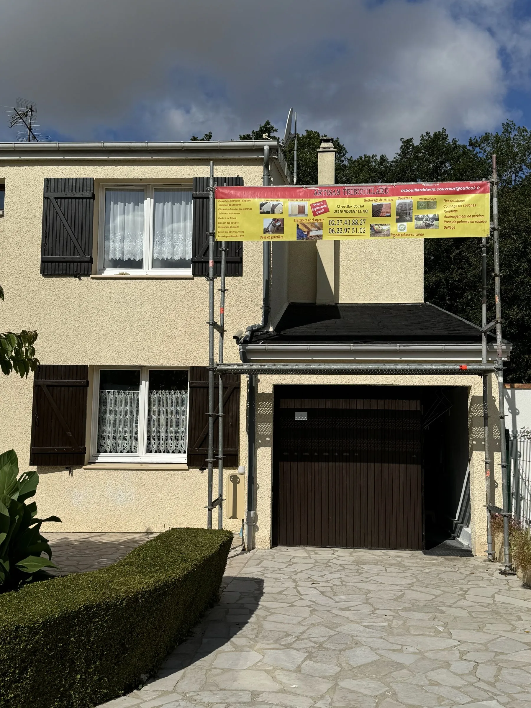Façade de pavillon en travaux, échafaudage avec la banderole de David Tribouillard