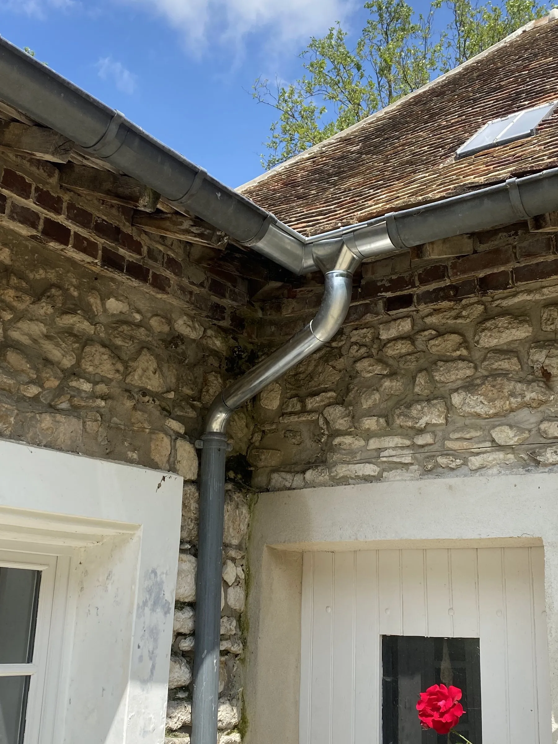 Gouttière et descente en zinc sous une toiture en tuiles plates
